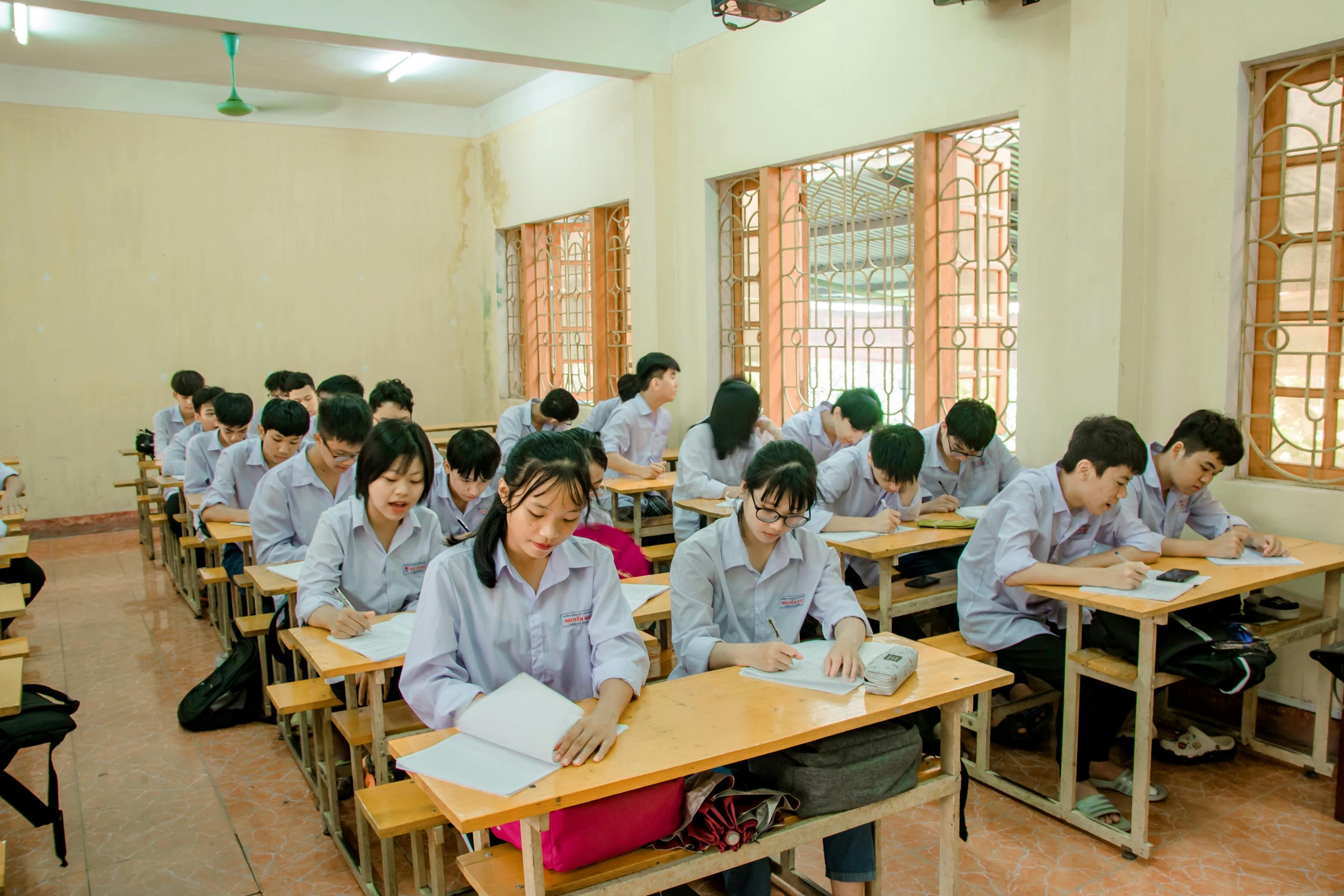 Students attentively studying in a bright classroom setting.